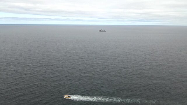4K Drone Tracking Shot of Small Boat Crossing North Sea with Survey Ship in Distance
