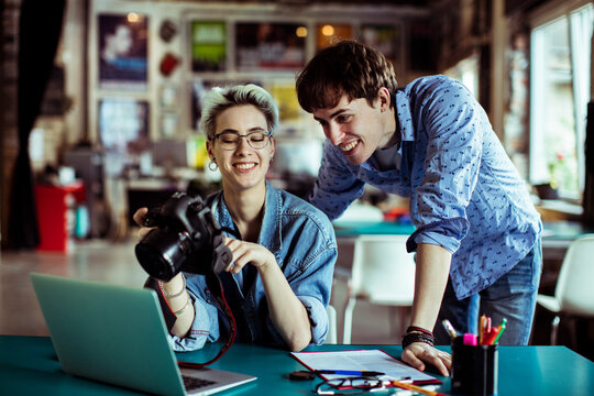 Two creative coworkers reviewing camera photos in studio