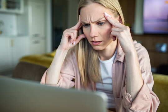 Stressed young woman concentrating on laptop at home