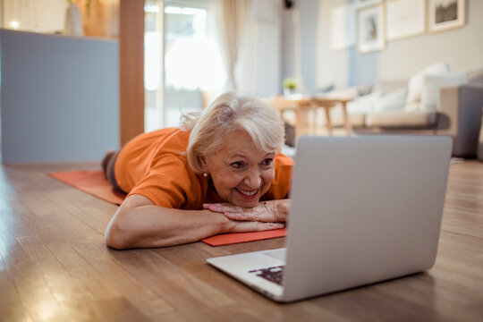 Smiling senior woman watching online yoga class at home