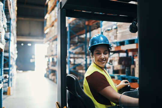 Smiling warehouse forklift operator wearing hard hat
