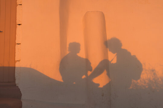 Shadow of man and  woman sitting on Santorini island at sunset 