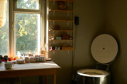 Sunny pottery studio with kiln and worktable
