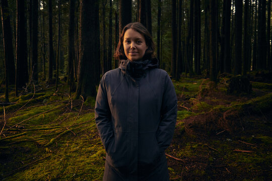 Woman stands in a forest during late afternoon light in October