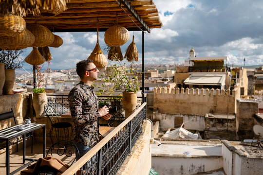 A male photographer looking at the cityscape from a terrace in F