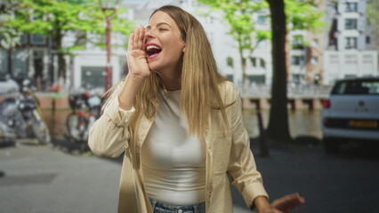 Fototapeta premium Woman cups hand to mouth shouting on a city street with parked bicycles and cars, wearing a casual shirt and denim jeans; joyful expression.