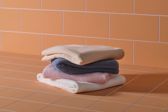 Stack of neatly folded bath towels in pastel colors on a tiled surface