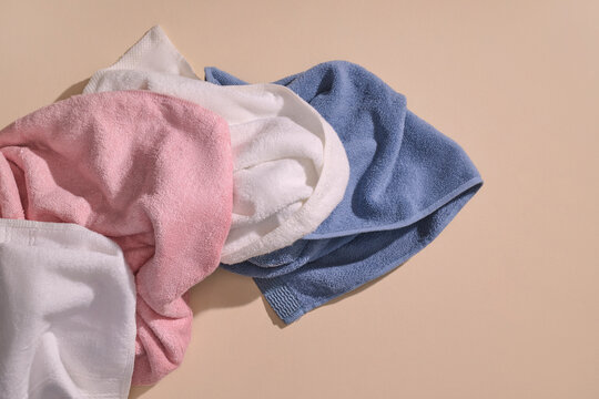 Pile of soft, fluffy towels in pink, white, and blue, neatly folded