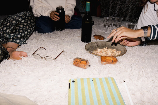 Friends snacking on pistachios and drinking wine at home at night