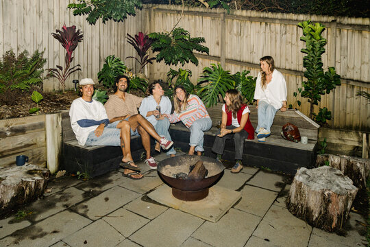 Friends gathered around fire pit at backyard party with flash