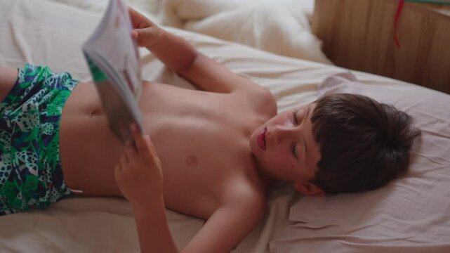 Boy reading book in bed at home, encouraging curiosity, literacy and joyful childhood learning