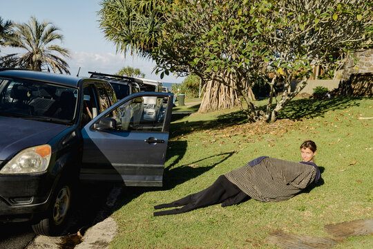 UGC Woman wrapped in surf poncho putting on wetsuit beside beach car