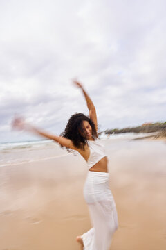 Woman dancing freely on beach celebrating vacation happiness
