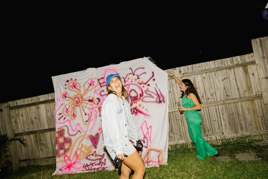 UGC Friends posing by epic graffiti sheet at backyard party