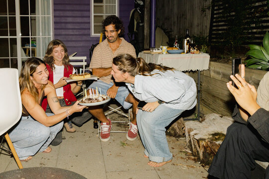 UGC Woman blowing candles during milestone backyard birthday