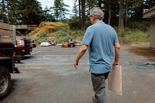 Candid senior man carrying wooden board in woodshop