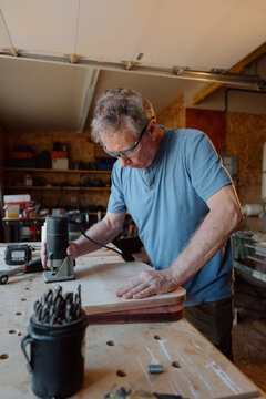 Candid carpenter working on wooden board in home workshop