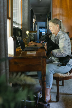woman sitting at her desk with dog on her lap 
