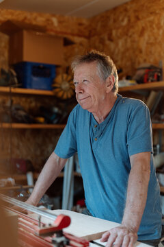 Candid portrait of a senior woodworker in his home workshop