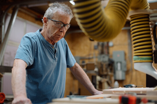 Older craftsman working in workshop with safety glasses