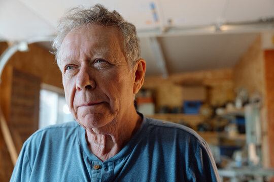 Thoughtful senior man portrait in his workshop, candid and real