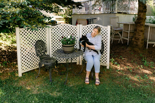 portrait woman sitting in her backyard with her dog.