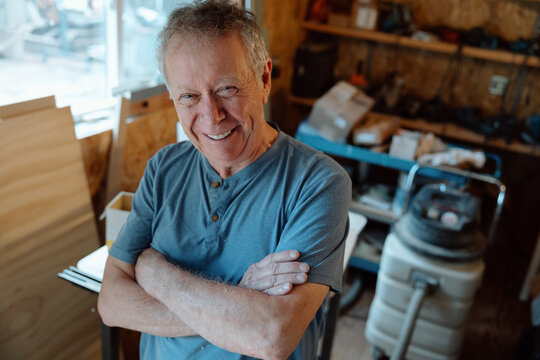 Candid smiling craftsman in workshop showing pride and warmth