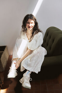 Girl sitting in studio adjusting shoes during the day