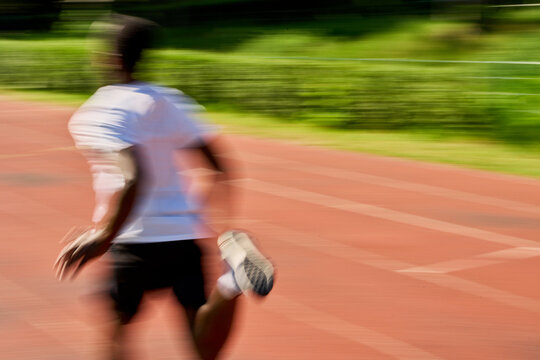 Runner Dashes on Track During Day With Bright Sunlight