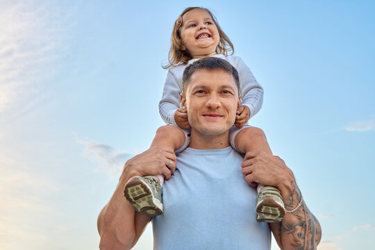 Father Carrying Happy Toddler on Shoulders Outdoors