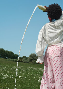 Young Woman Pouring Milk in Sunny Meadow During Summer Picnic