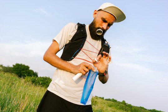 Runner Prepares Drink in a Bottle During Outdoor Activity 