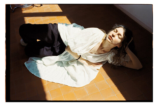 Woman in studio laying on the floor with sunlight around her
