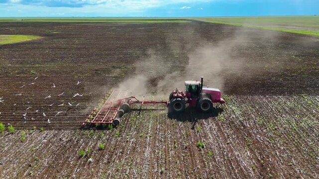 Tractor cultivating the soil in a field before planting, drone view.