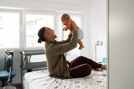 Father playing with baby on bed