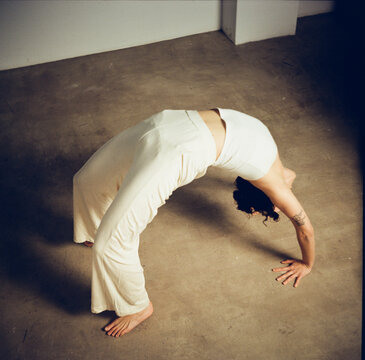 Woman Performs Yoga Pose in Studio on a Gray Floor