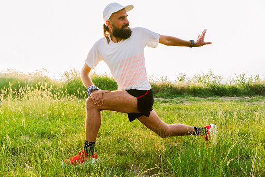 Runner Stretches in Open Field During Evening Sun