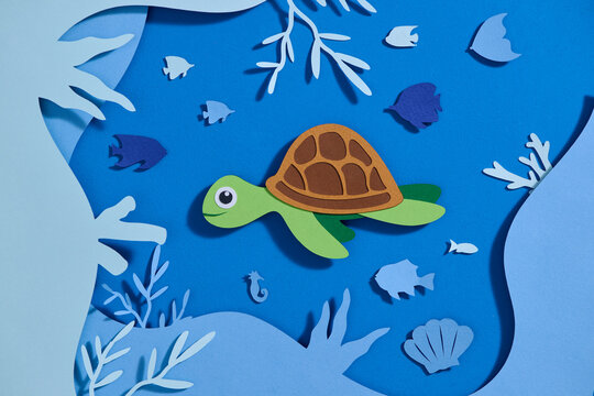 Vibrant paper cutout of Turtle in a blue aquatic setting with fish