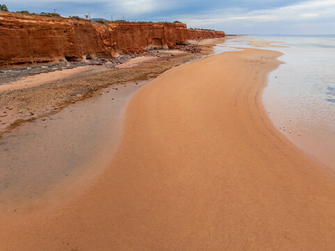 Deserted sand beach below rugged cliffs stretching toward the horizon