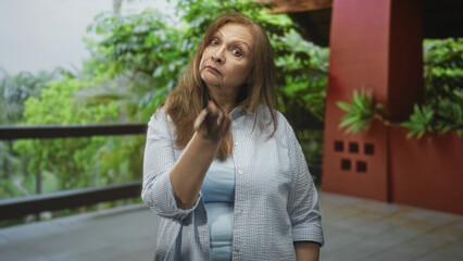 Fototapeta premium Woman pinches nose with hand on building balcony to block strong smell and cover nostrils; disgust aversion.