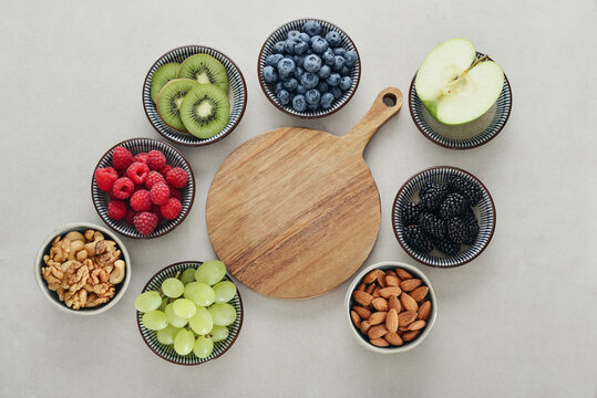 Healthy antioxidant rich fruits, berries and nuts on light background