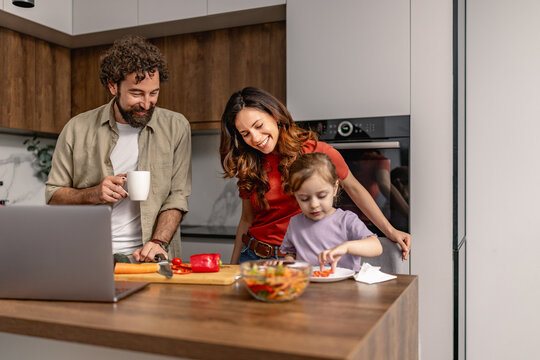 Family cooking together in modern kitchen with parents and child preparing a healthy meal