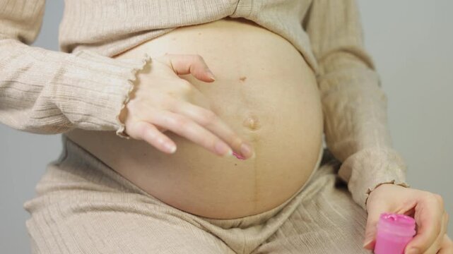 Expecting mother painting a sweet pink heart on her belly, expressing love and excitement for her upcoming baby girl.