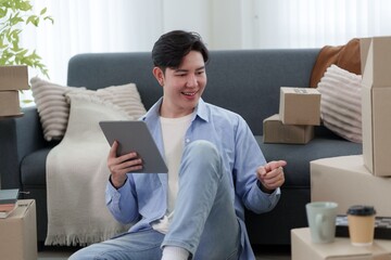 Young Asian entrepreneur managing online store orders with tablet surrounded by shipping boxes at home © snowing12