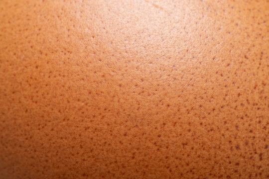 Macro Close-Up of Brown Eggshell Texture,A detailed macro close-up photograph showcasing the natural, porous, and speckled texture of a brown chicken eggshell surface, highlighting organic patterns an