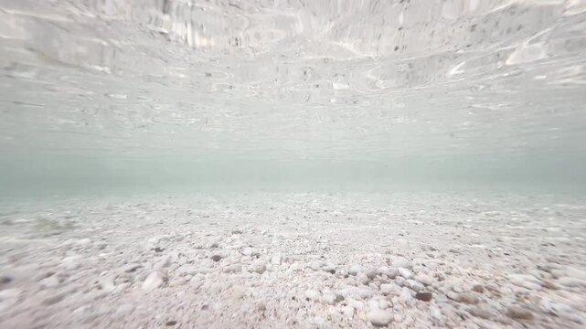 Underwater gravel and pebble seabed with rippling water surface in shallow coastal ocean, natural marine background, 4K_1_IMG_5205_15s_0,00.MOV.mov