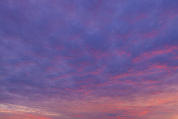 Fototapeta premium Vibrant Orange and Purple Sunset Sky with Dramatic Clouds,Stunning colorful sunset sky filled with dramatic golden orange and purple clouds, creating a peaceful and serene natural background.