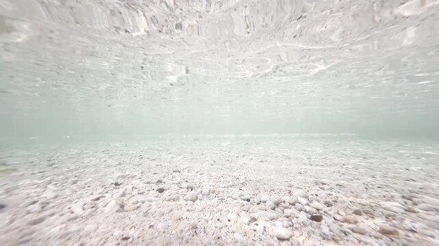 Underwater gravel and pebble seabed with rippling water surface in shallow coastal ocean, natural marine background, 4K_2_edit_IMG_5205_18s_0,15.MOV.mov