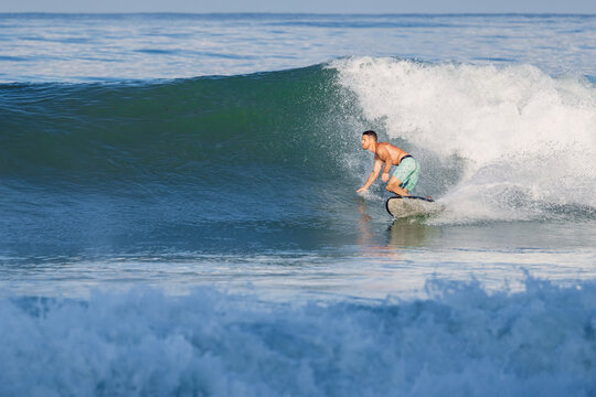 Surfer male riding a powerful ocean wave on a sunny day, surfing on perfect swell
