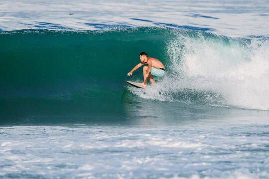Surfer male riding a powerful ocean wave on a sunny day, surfing on perfect swell